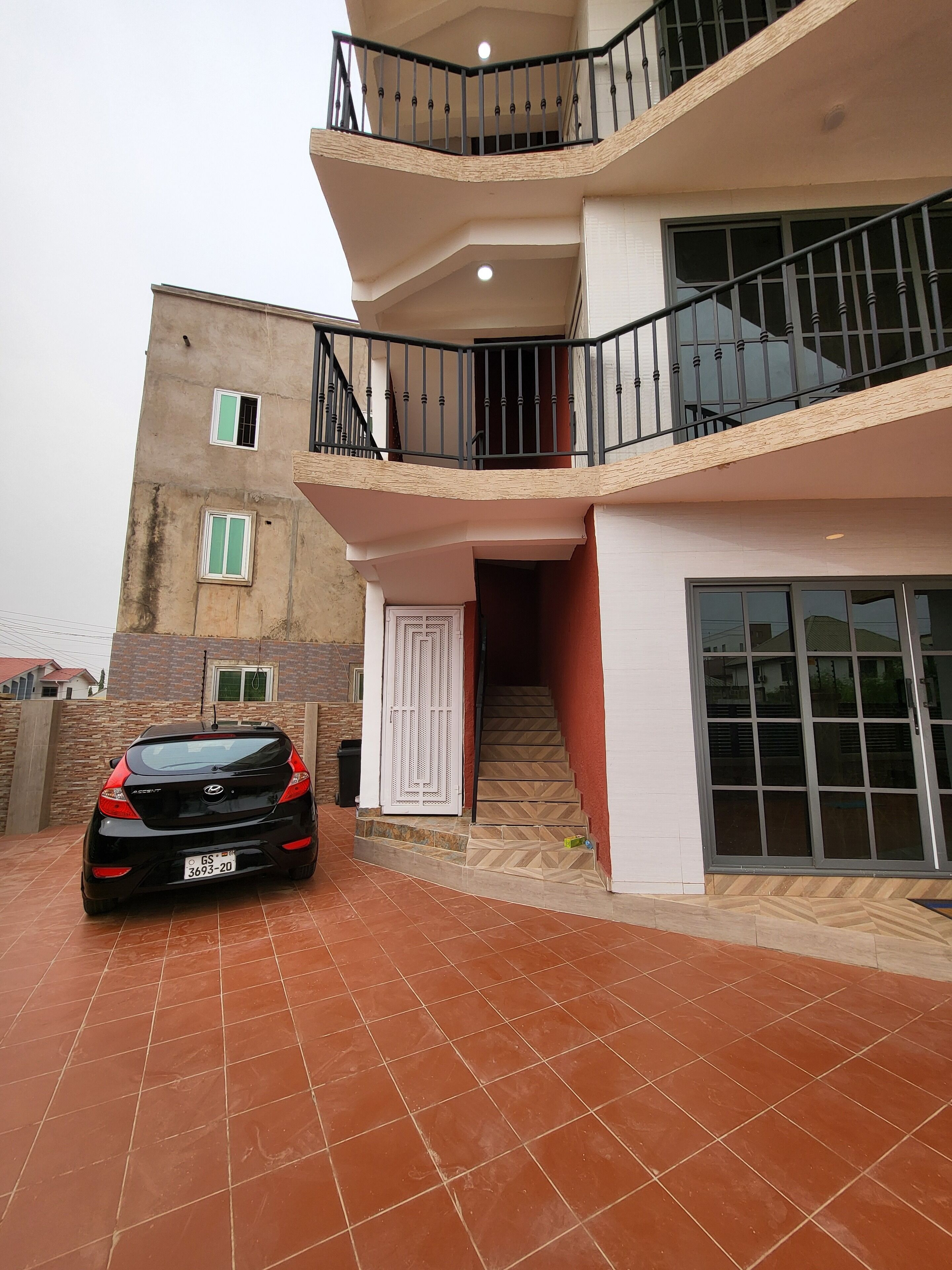 Um edifício residencial de vários andares com um carro estacionado na entrada.