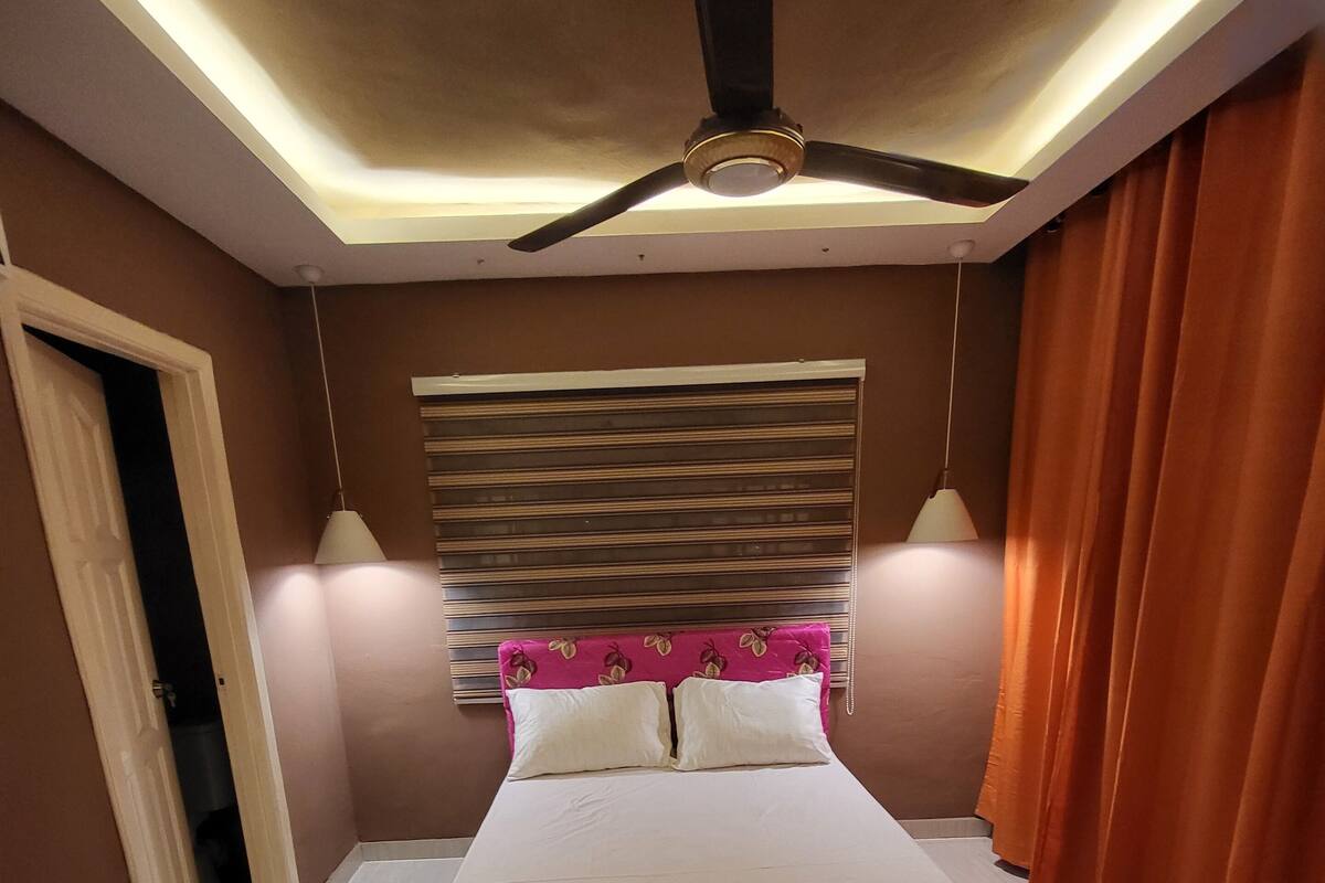 A bedroom with a bed, ceiling fan, and two bedside lamps.