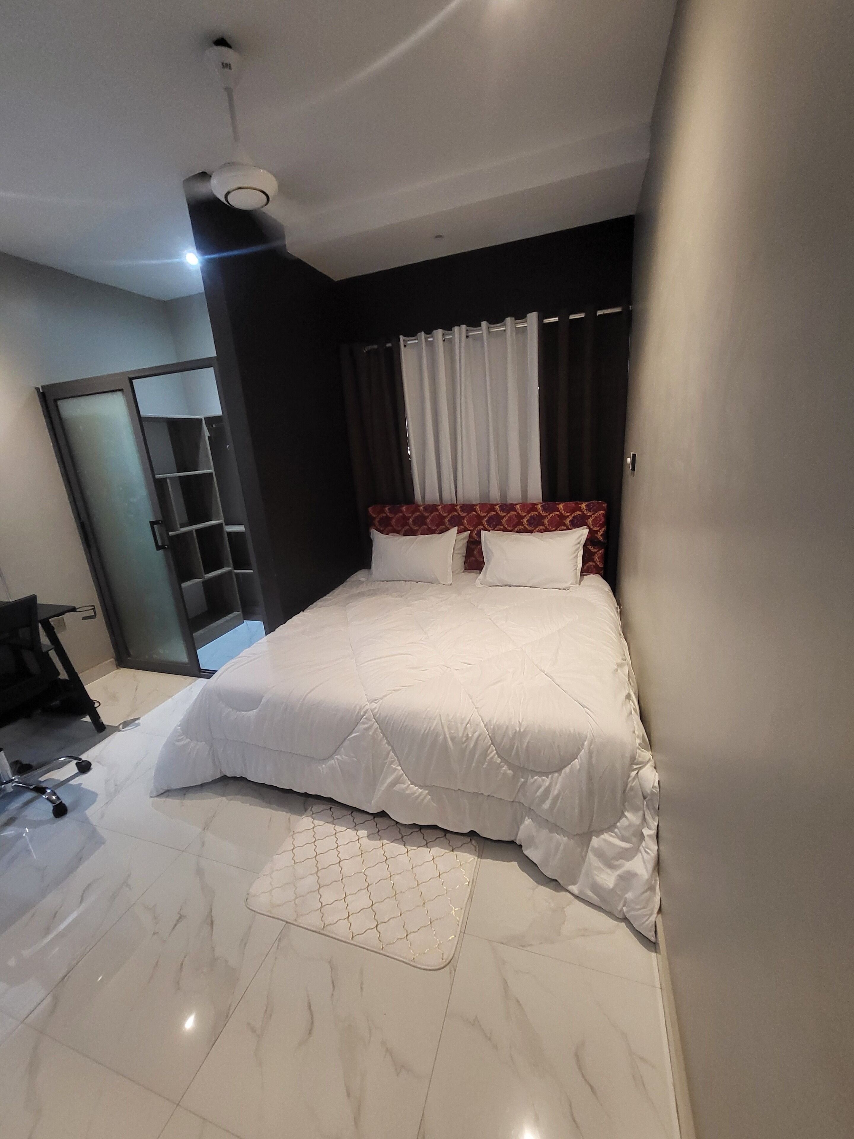 A hotel room with a bed, a desk, and a wardrobe.