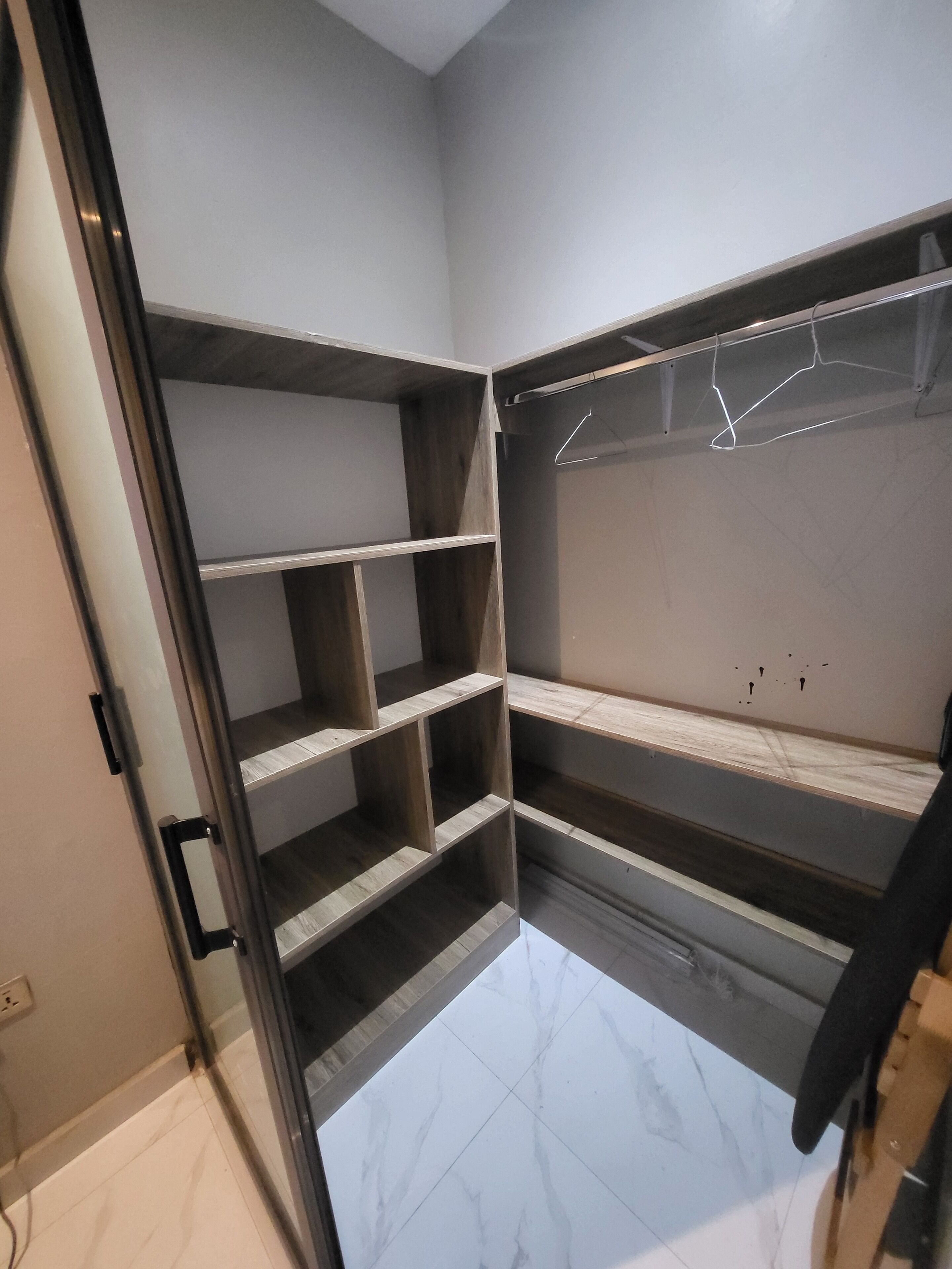 A walk-in closet with open shelving, a hanging rod, and a tiled floor.