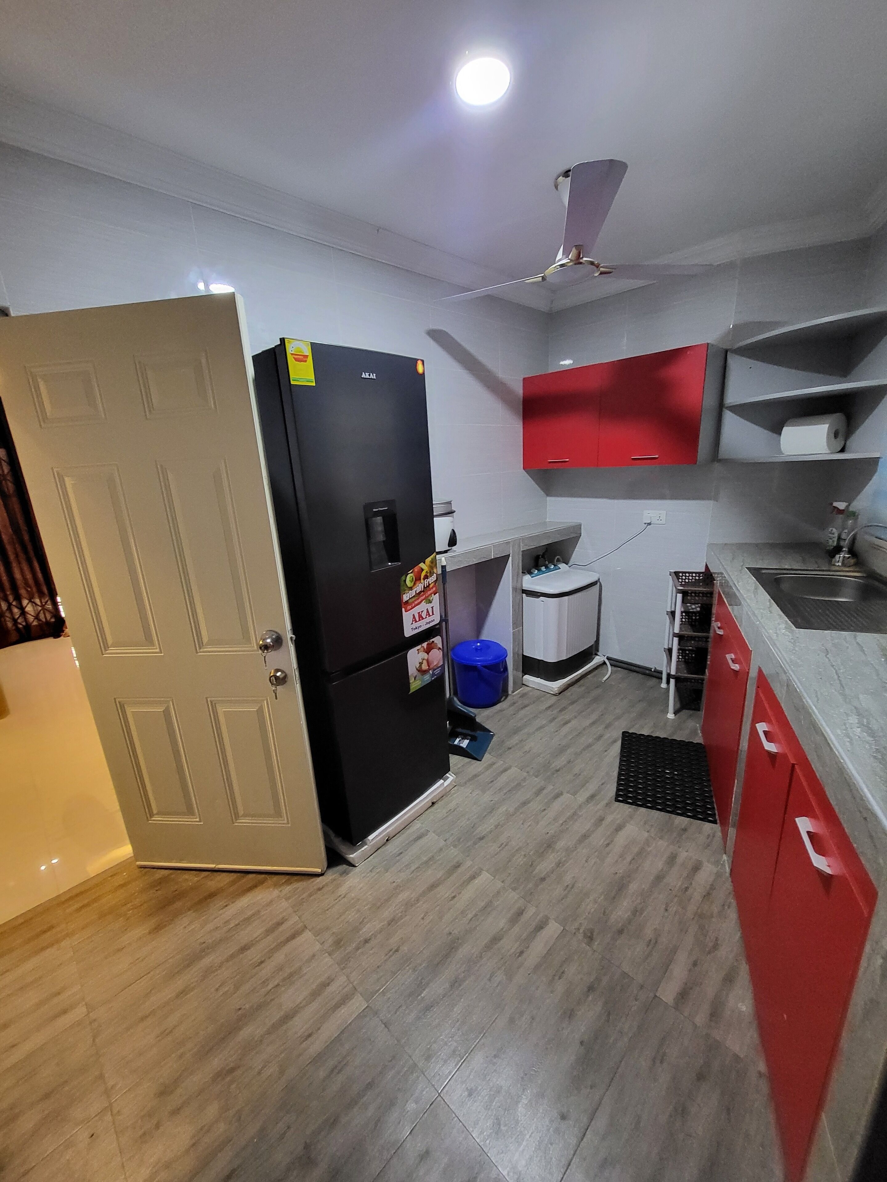 A compact kitchen with a refrigerator, a sink, and red cabinets.