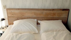A bed with a wooden headboard, white bedding, and a lamp on a bedside table. - Amsterdam Farm Lodge (Amsterdam)