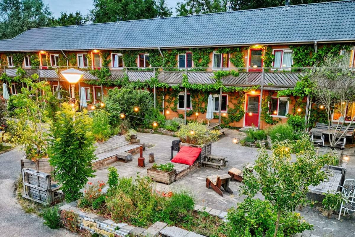 A two-story building with a covered patio area, outdoor seating, and string lights.
