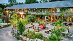 Un bâtiment à deux étages doté d’un patio couvert, d’un espace extérieur aménagé pour s’asseoir et de guirlandes lumineuses.