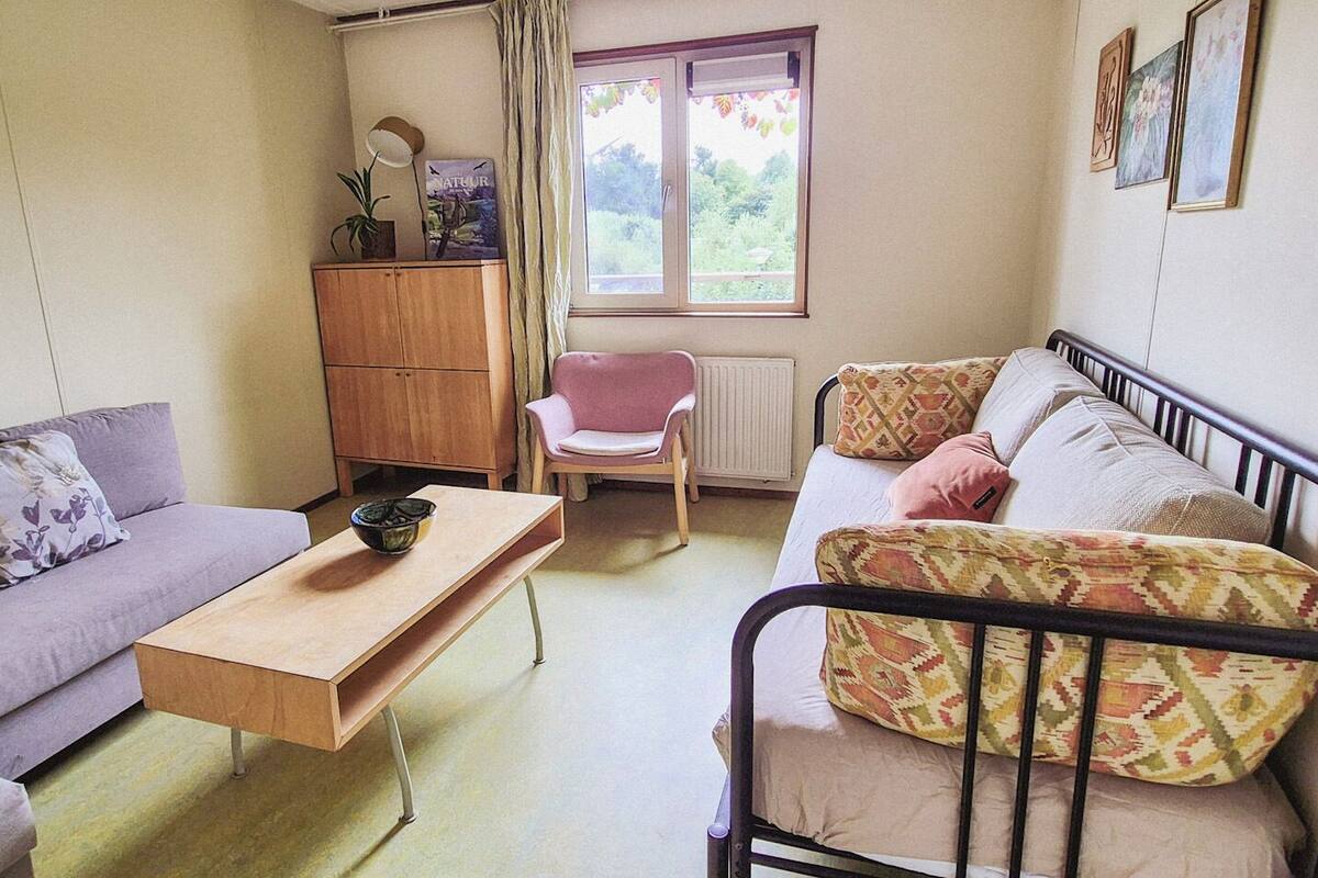 A compact living room with a sofa, a chair, a small table, and a bed.