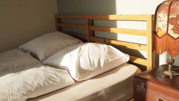 A bed with a wooden headboard, a suitcase, and a lamp on a bedside table.