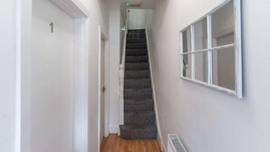 En smal hall med en matta som täcker trappan som leder upp till ett rum.