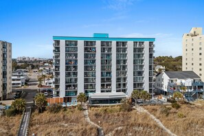 A multi-story hotel with balconies, a central courtyard, and a view of the surrounding area. - Oceanfront 3-bedroom end unit in sought after Windy Hill Beach (North Myrtle Beach)
