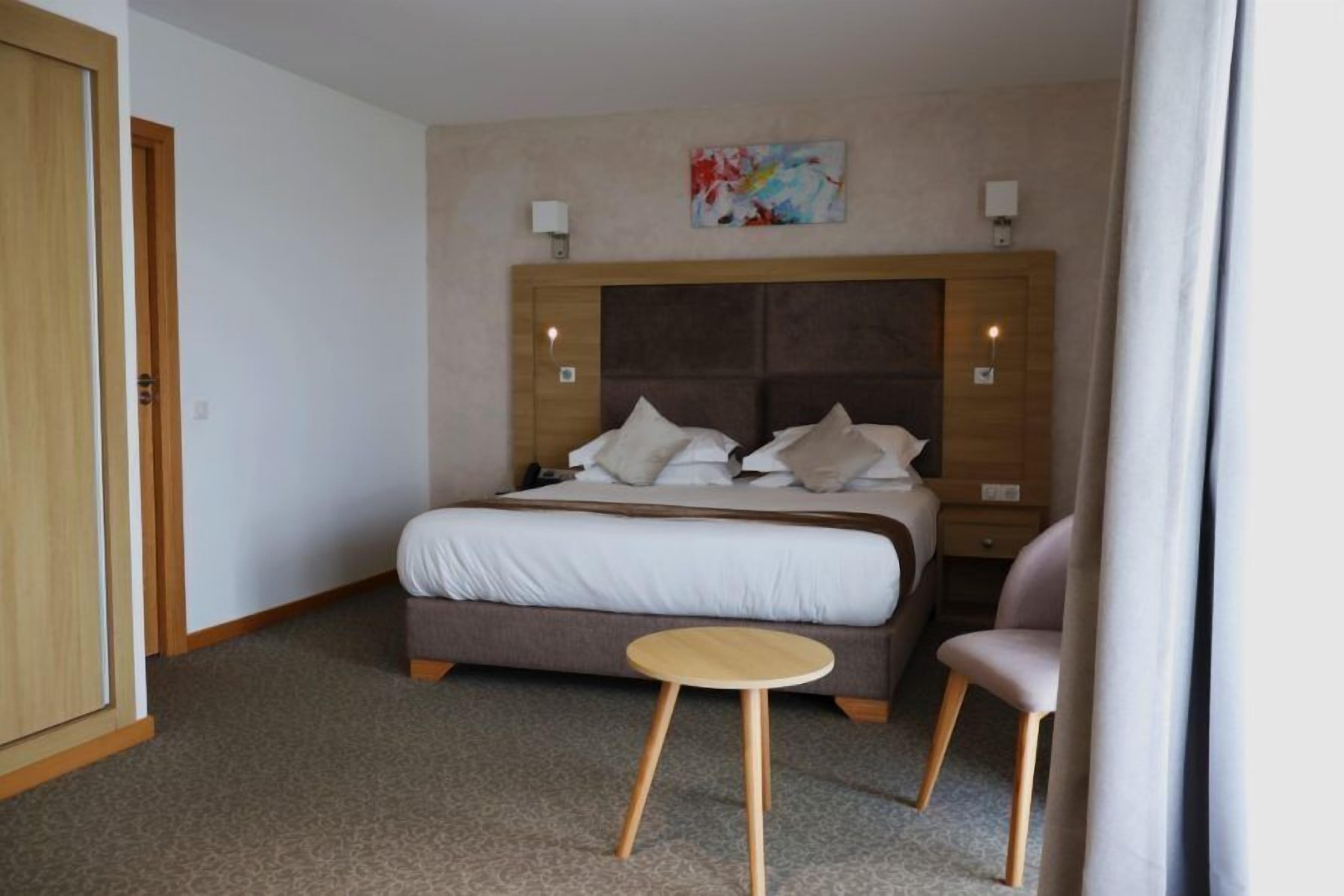 Una camera d'albergo con un letto, comodini, un tavolino rotondo e una sedia.
