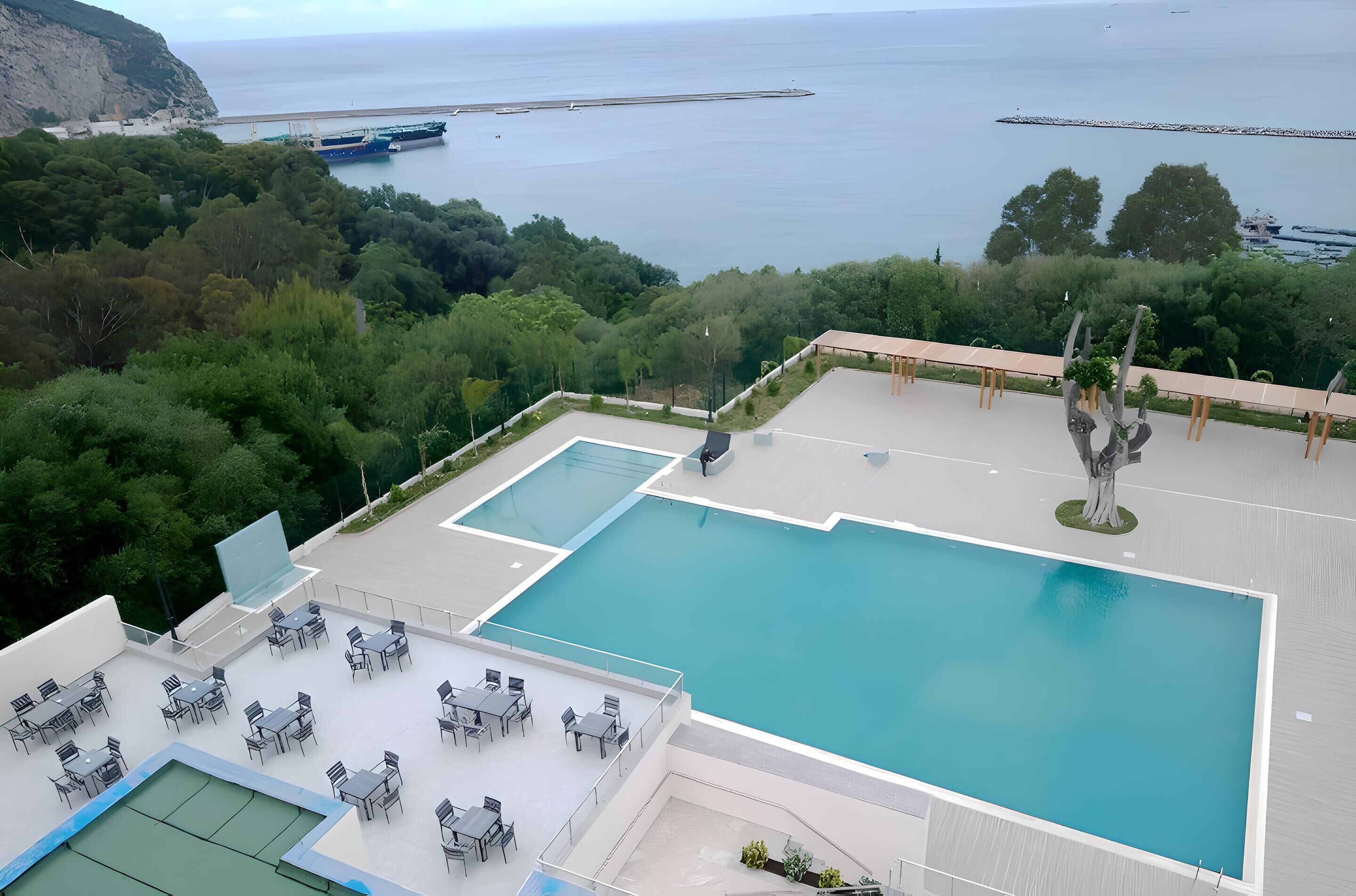 A rooftop pool with outdoor seating and a view of the sea.