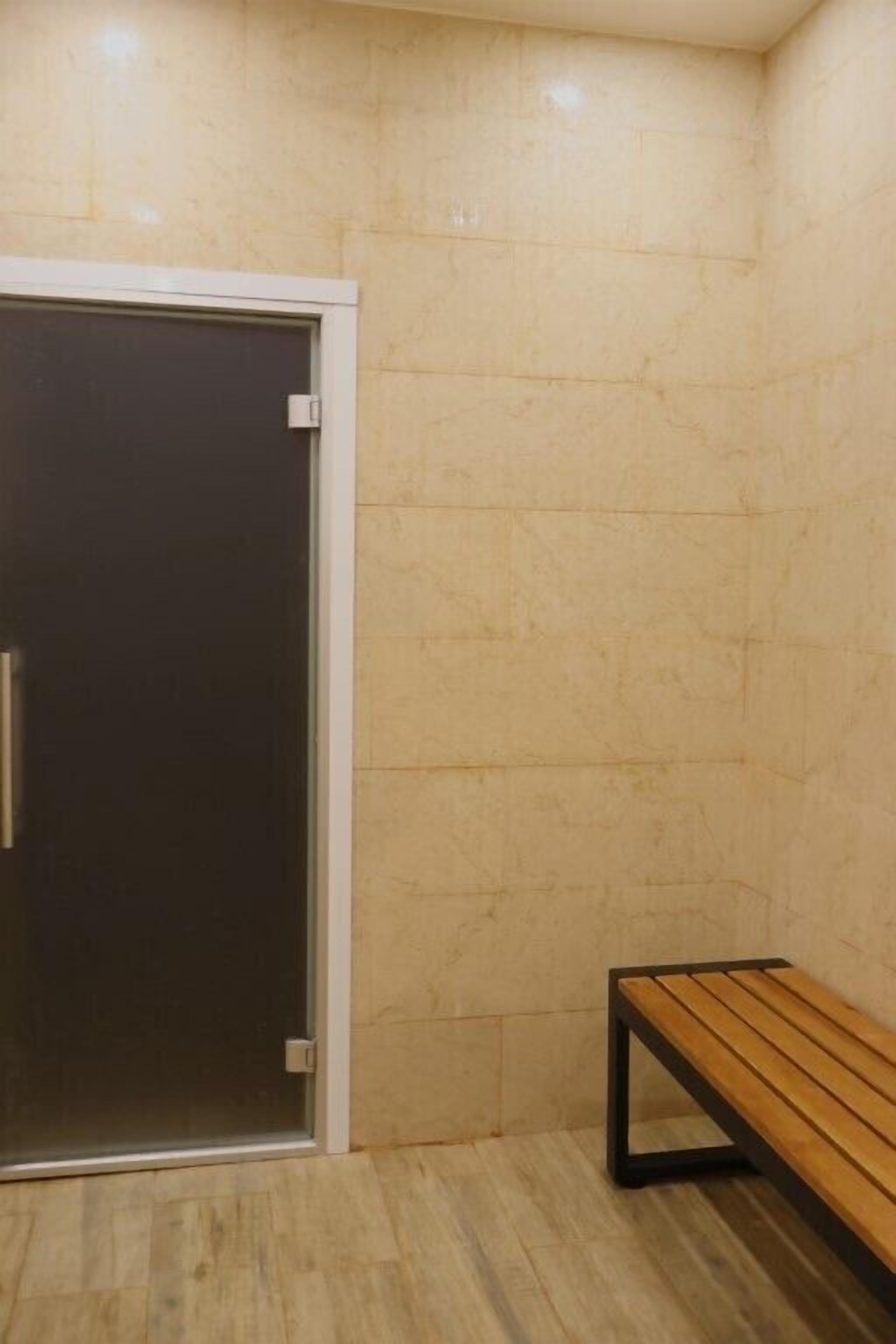 A room with a wooden bench, a door with a glass panel, and tiled walls.