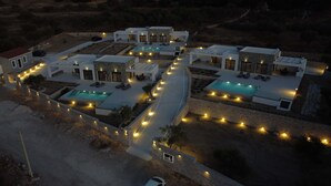 Ein modernes Resort mit mehreren Swimmingpools, Außenbereichen zum Sitzen und gut beleuchteten Wegen.