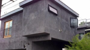 Een modern gebouw met een grijze gevel, een klein raam en een garagepoort.