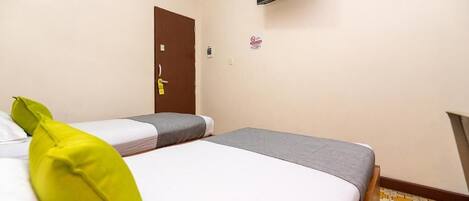 Camera d'albergo con due letti, una televisione montata a parete e una porta con serratura.