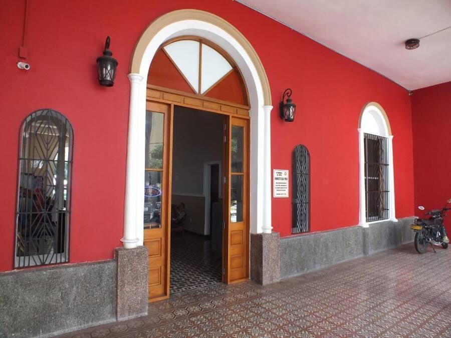 A red building with a wooden door and two arched windows.