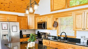 Una cocina moderna con armarios de madera, un refrigerador de acero inoxidable, un microondas y una isla grande con taburetes.