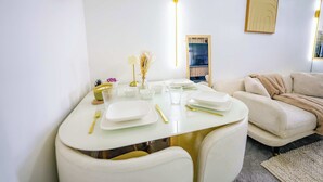 Un coin repas avec une table ronde dressée pour quatre personnes, un canapé, une lampe fixée au mur et un tableau encadré.