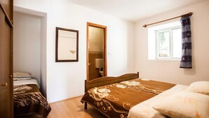 Une chambre à coucher avec un lit, une fenêtre avec des rideaux, une table de chevet et un miroir.