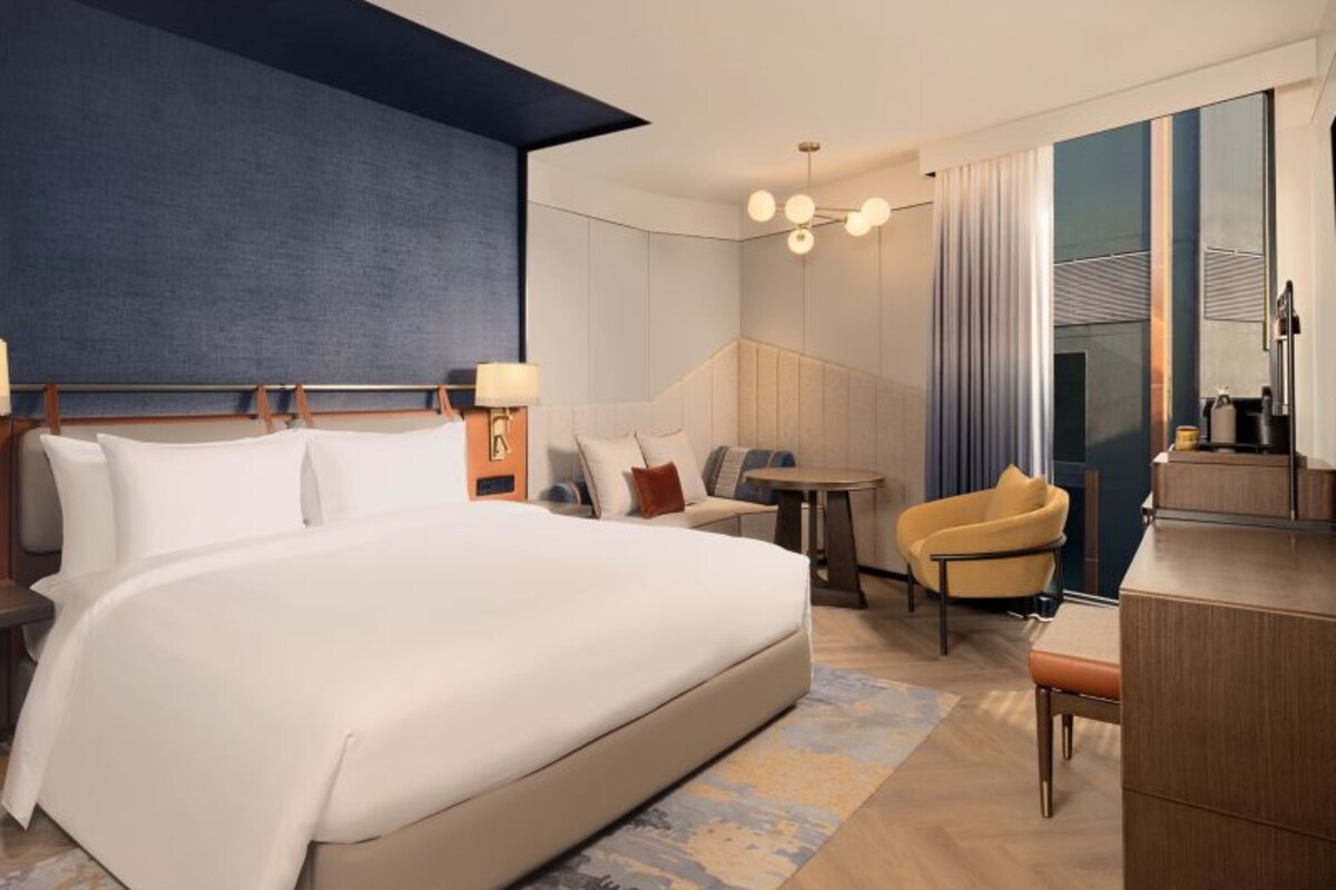 Een moderne hotelkamer met een groot bed, een zithoek met een tafel en een bureau.