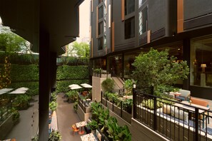 Une terrasse extérieure à plusieurs niveaux, aménagée avec des espaces pour s’asseoir, de la verdure et offrant une vue sur l’intérieur du bâtiment.