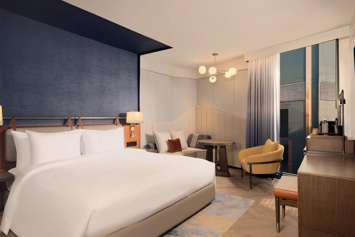 Una habitación de hotel moderna con una cama grande, una zona de estar con una mesa y un escritorio.