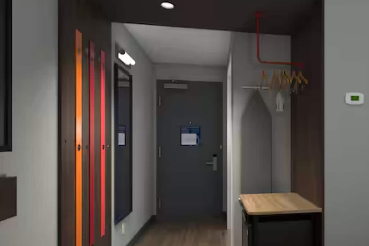 En hall med en dörr, ett litet bord och en väggmonterad lampa.
