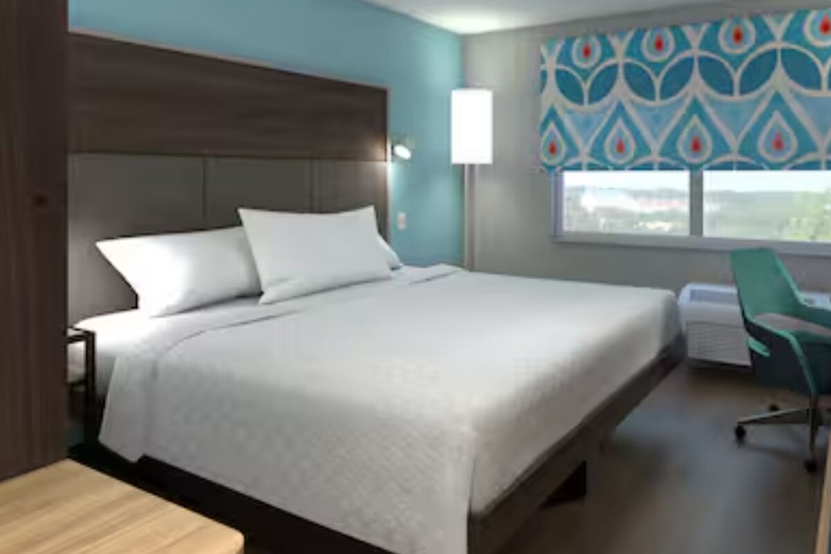Habitación de hotel con cama, escritorio, silla y ventana con vistas.