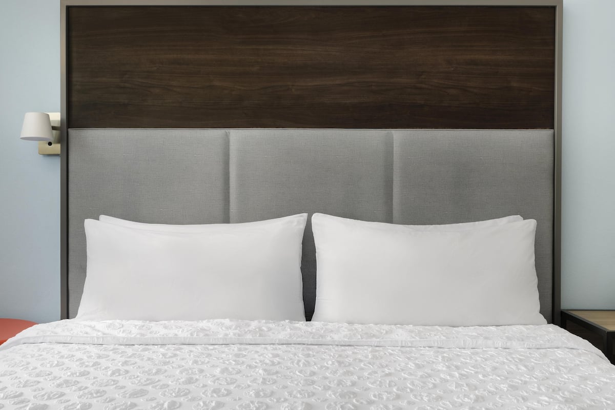 A bed with a headboard, pillows, and a textured bedspread.
