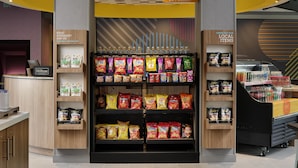 A snack display with various chips and snacks, a 24/7 market sign, and a Hilton Honors sign. - Tru By Hilton Ridgeland Jackson (Ridgeland)