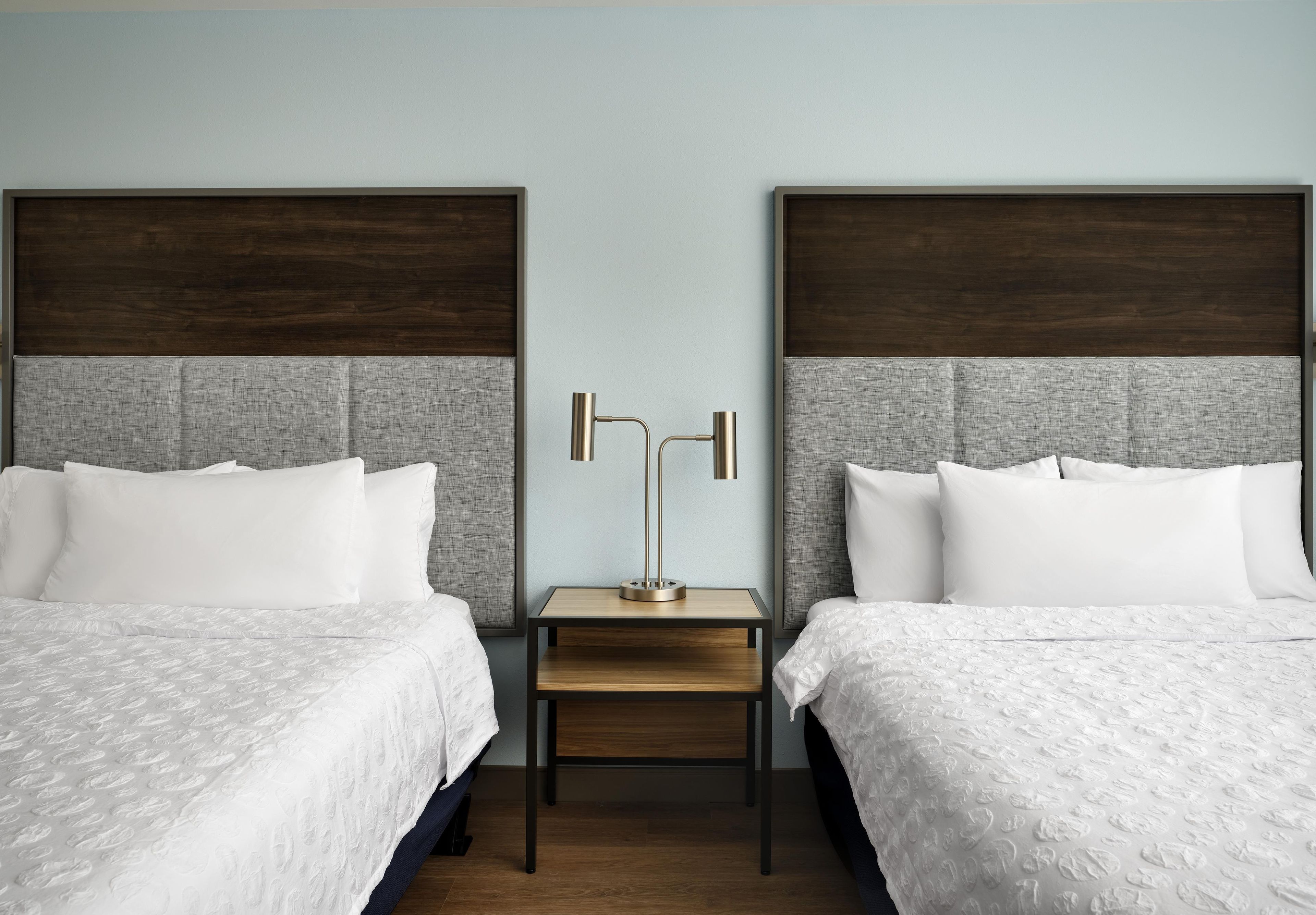 Une chambre d’hôtel avec deux lits, une table de chevet et une lampe.