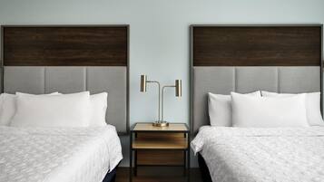 Une chambre d’hôtel avec deux lits, une table de chevet et une lampe.