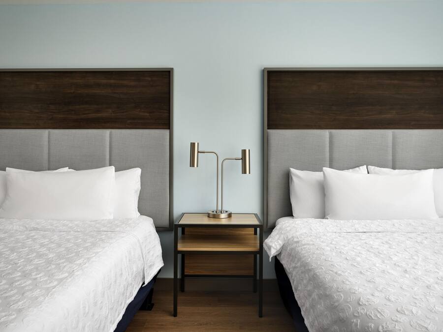 Une chambre d’hôtel avec deux lits, une table de chevet et une lampe.