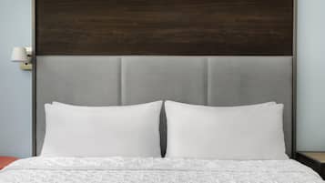 A bed with white bedding and a headboard with a textured grey panel.