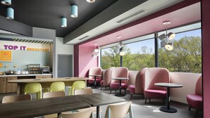 A modern breakfast area with a counter, seating, and large windows. - Tru By Hilton Ridgeland Jackson (Ridgeland)