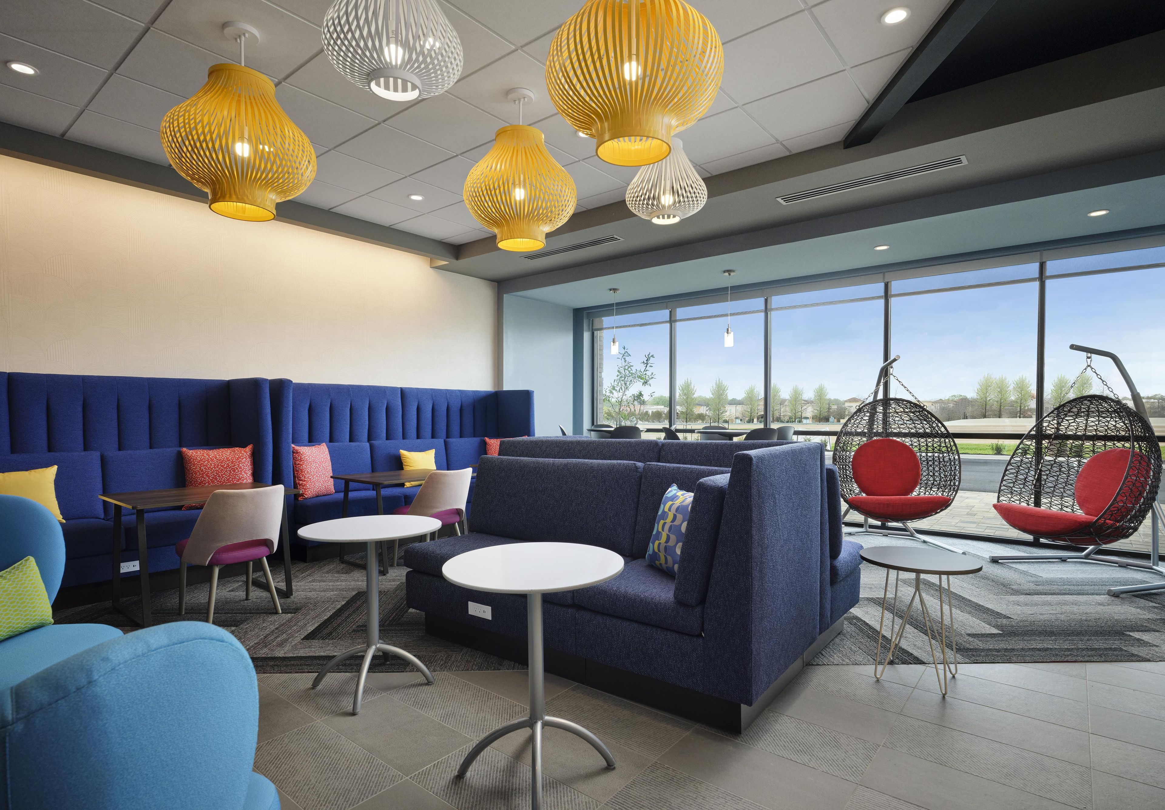 Un espacio lounge moderno con asientos, mesas y sillas colgantes.