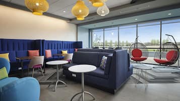Un espacio lounge moderno con asientos, mesas y sillas colgantes.