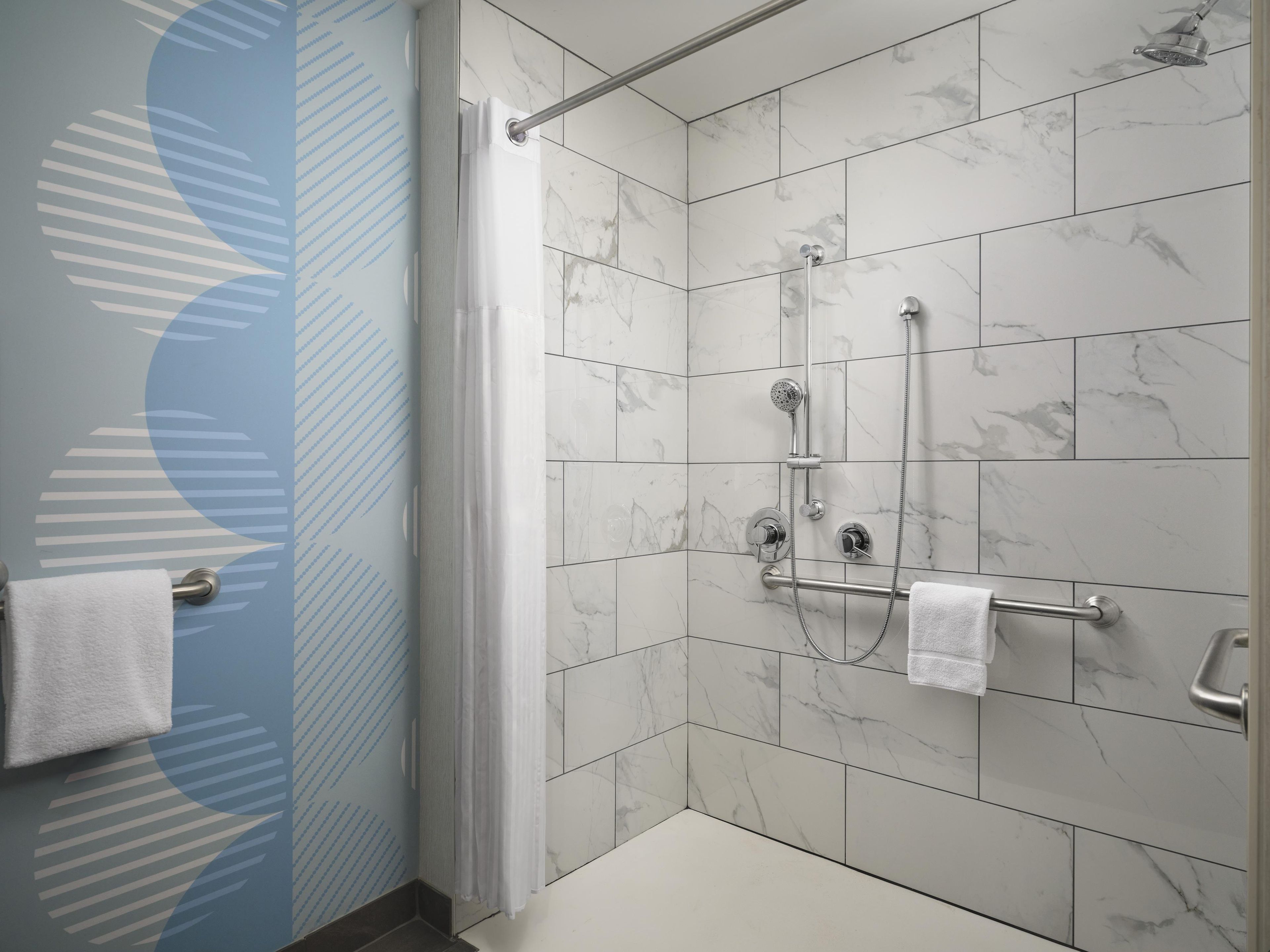 A shower area with a glass door, marble tiles, and a towel rack.