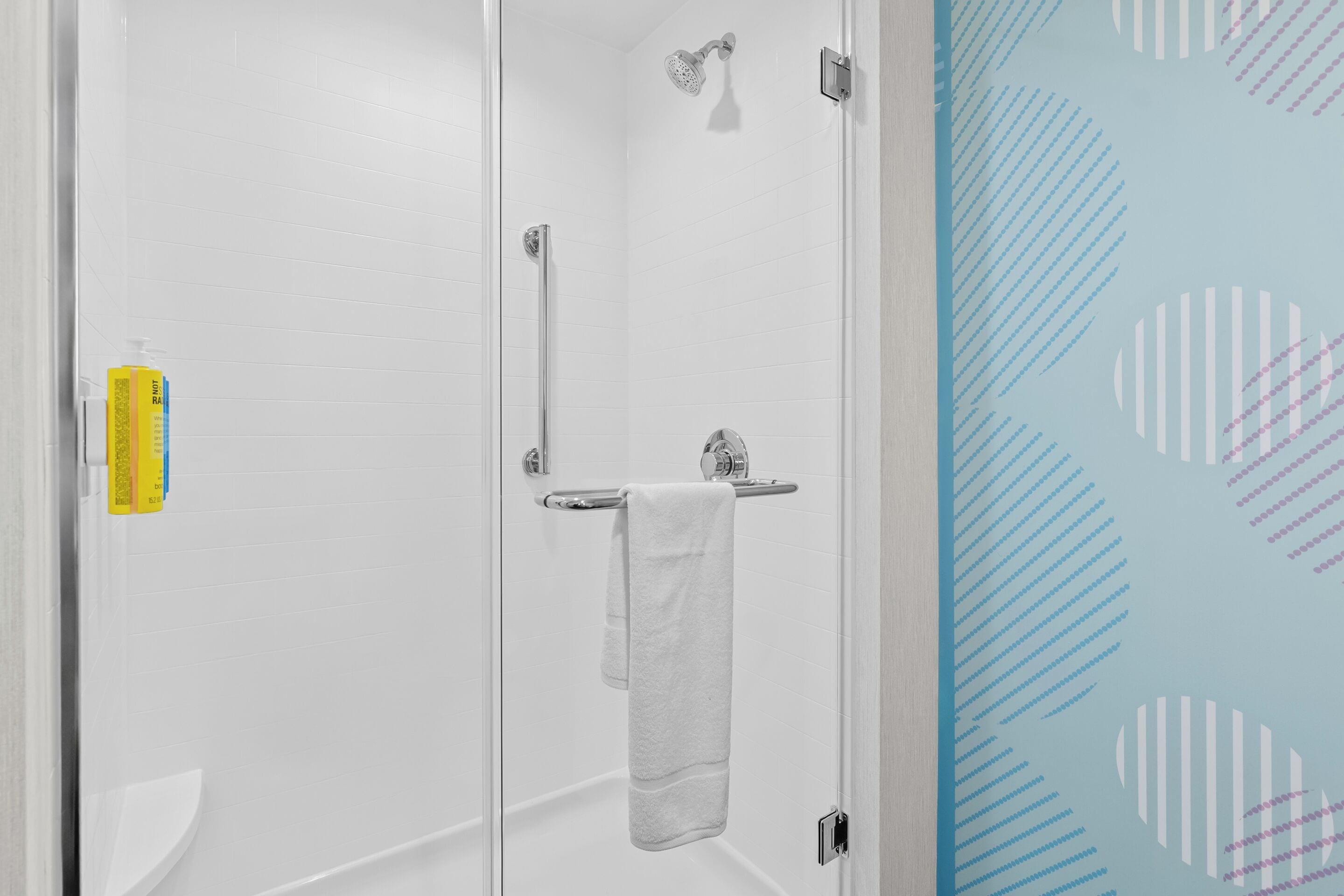 Un baño con cabina de ducha de vidrio, inodoro blanco y perchero para toallas.
