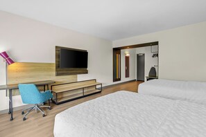A hotel room with a bed, a desk with a chair, a TV mounted on the wall, and a mirror. - Tru By Hilton Princeton (Princeton)