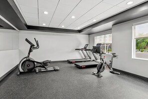 A gym with stationary bikes and treadmills, a large window, and a ceiling with recessed lighting. - Tru By Hilton Princeton (Princeton)