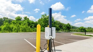 Ein Parkplatz mit Ladestationen für Elektrofahrzeuge, markierten Stellplätzen und blauem Himmel.
