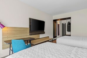 A hotel room with a bed, a desk, a chair, a television, and a bathroom with a mirror and towel rack. - Tru By Hilton Princeton (Princeton)