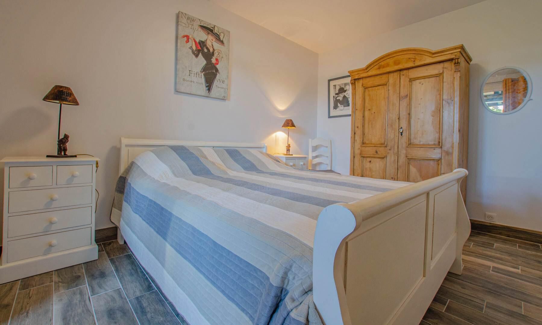 A bedroom with a bed, a dresser, a wardrobe, and a poster on the wall.