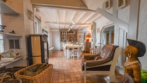 Een gezellige woonkamer met een open haard, een eethoek en een keuken op de achtergrond.