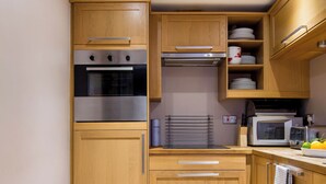 Une cuisine compacte avec des meubles en bois, un four en acier inoxydable, un four à micro-ondes et un grille-pain.