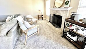 A living room with a sofa, armchairs, a fireplace, a coffee table, and a bookshelf.