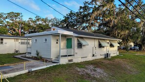 A single-story mobile home with a green door, a small porch, and a covered front porch area. - Studio, mini fridge/coffee DT Safety Harbor (Safety Harbor)