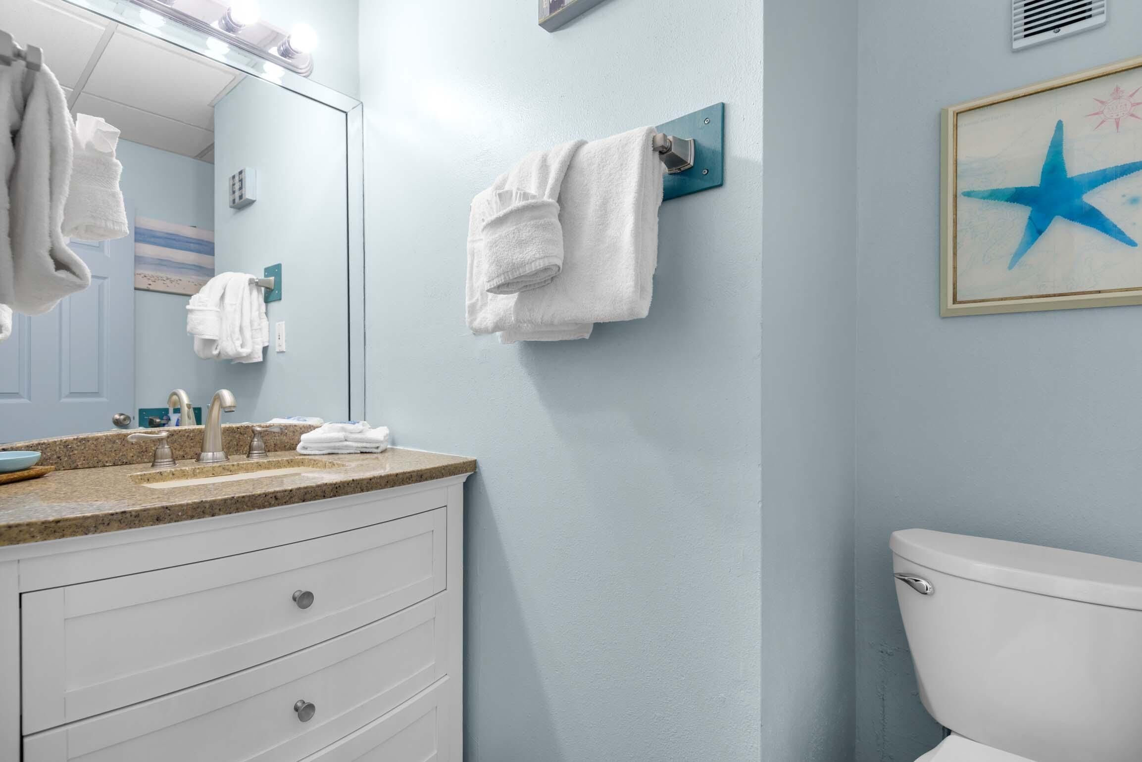 A bathroom with a sink, mirror, towel rack, and toilet.