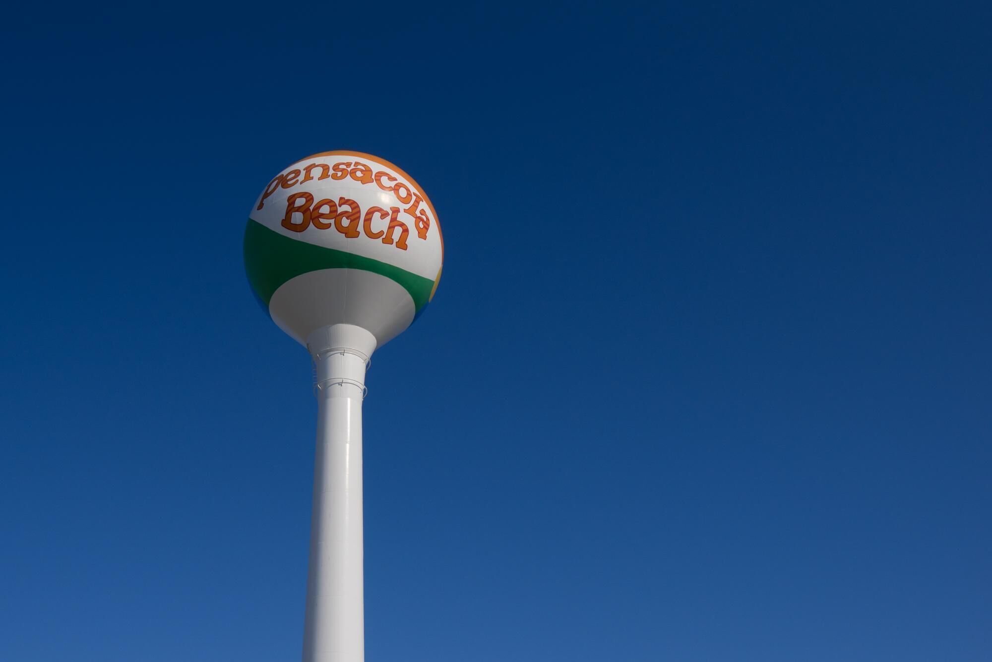 Un ballon de plage sur lequel est inscrit le texte « Pensacola Beach », fixé à un poteau blanc.