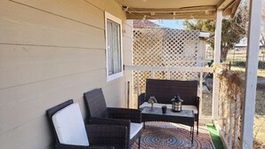 Un patio couvert aménagé avec des meubles en osier et un tapis à motifs.